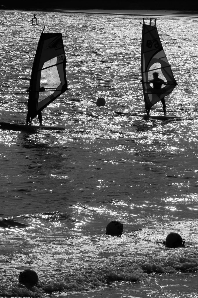 Grands voiliers se profilant sur l'eau scintillante au coucher du soleil.