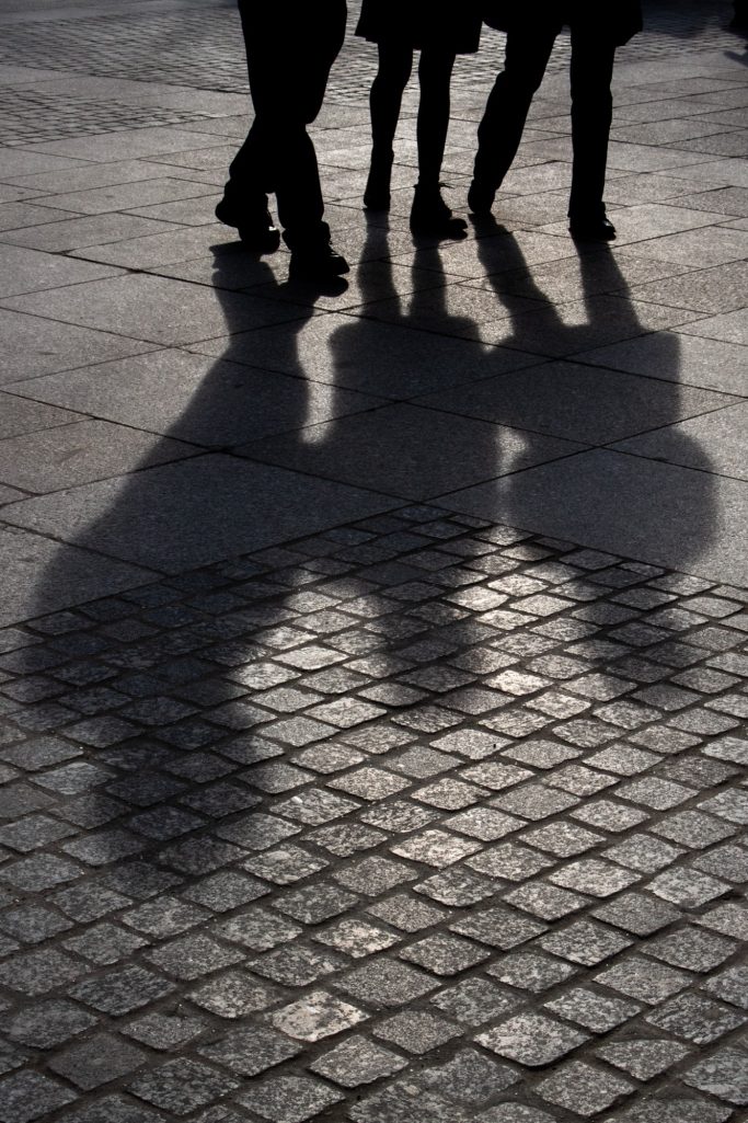Silhouettes de personnes marchant sur un sol en pavés.