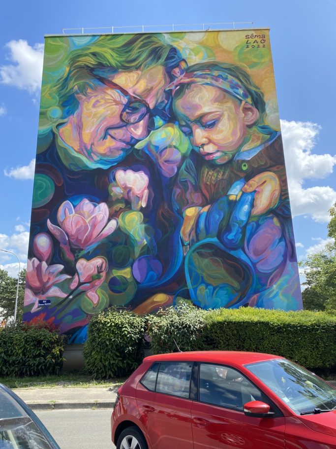 Fresque colorée représentant une femme et une enfant arrosant des fleurs.